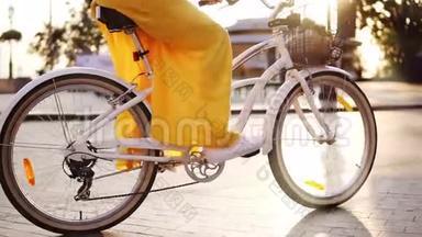 白色城市自行车`车轮旋转的特写镜头。 有铃铛，篮子和花的城市自行车。 无法辨认的妇女